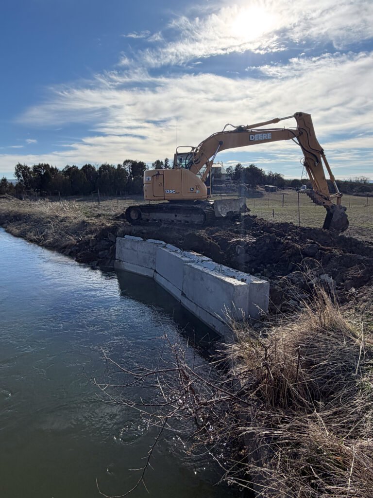 Excavator working beside a concrete-lined water channel